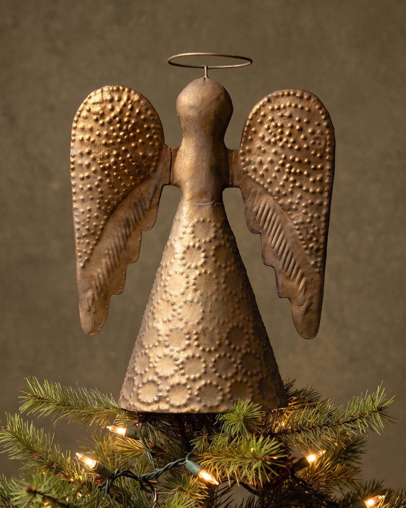 A bronze gold angel tree topper with textured wings and a halo, displayed on a lit Christmas tree against a warm brown background.